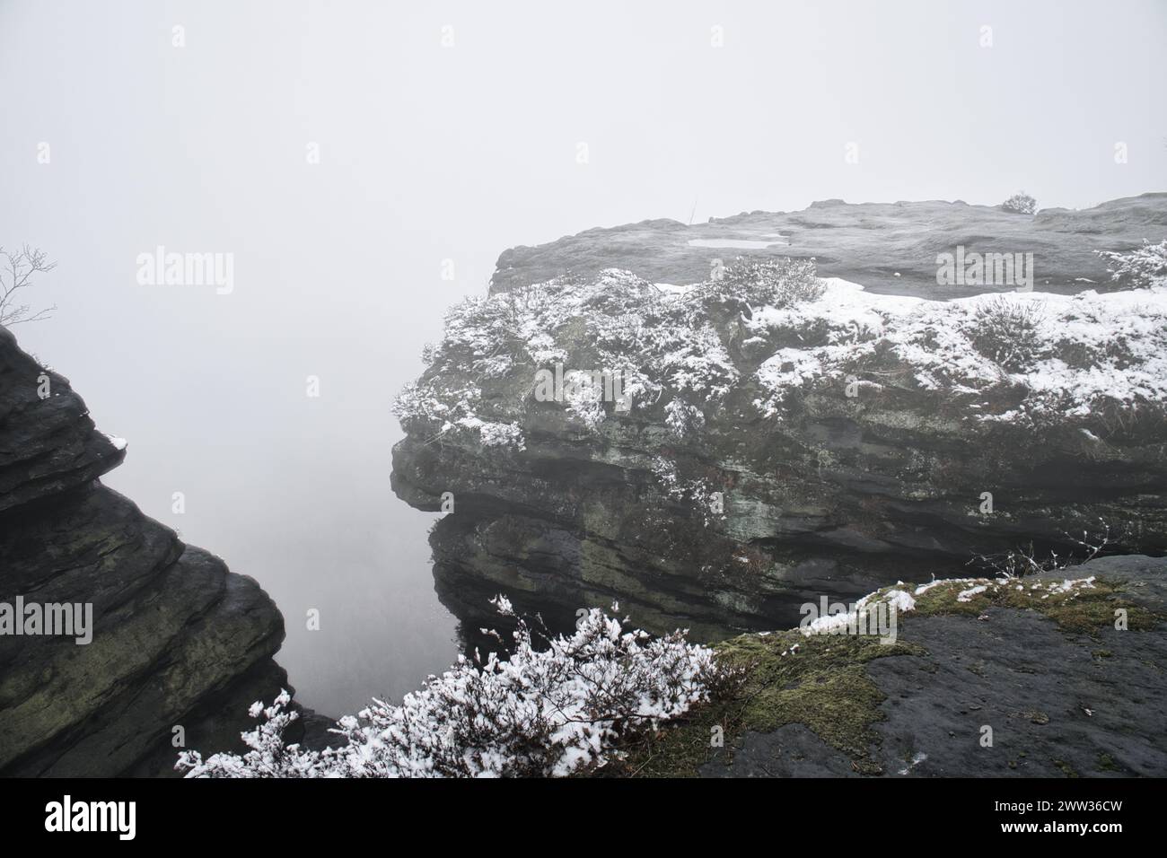 Sur le grand Zschirnstein dans le brouillard. Roche recouverte de neige. Point de vue pendant une randonnée. Du parc naturel dans les montagnes de grès de l'Elbe. Paysage dans Banque D'Images