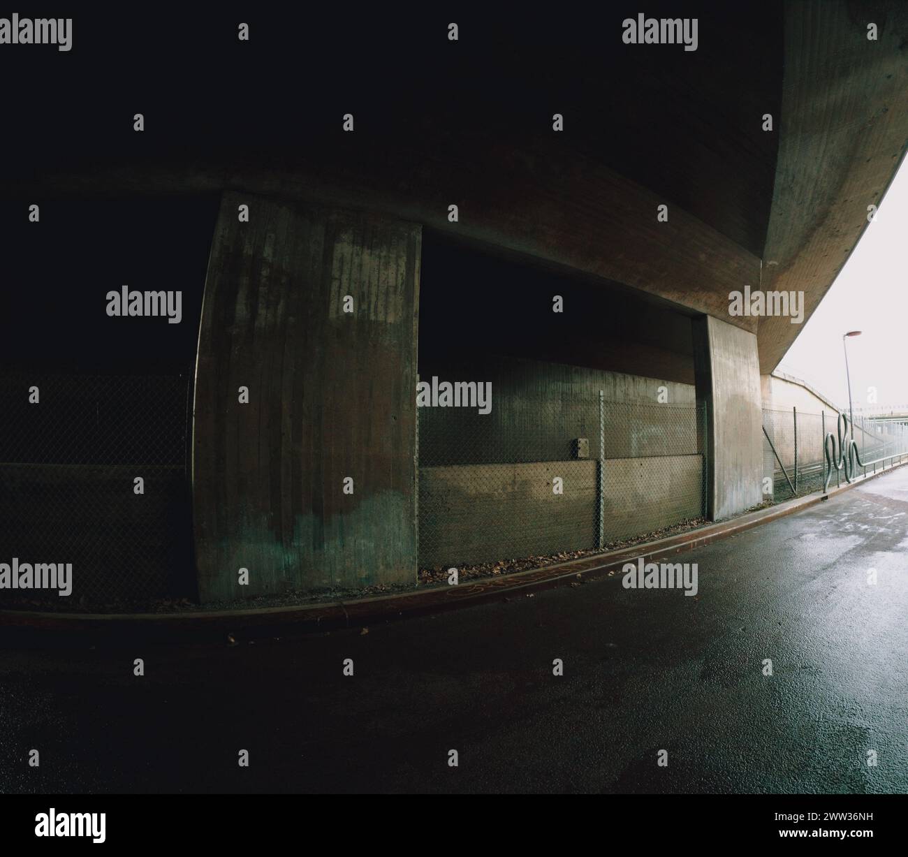 Passage souterrain urbain vide dans du béton brut et de l'asphalte humide un jour de pluie. Banque D'Images