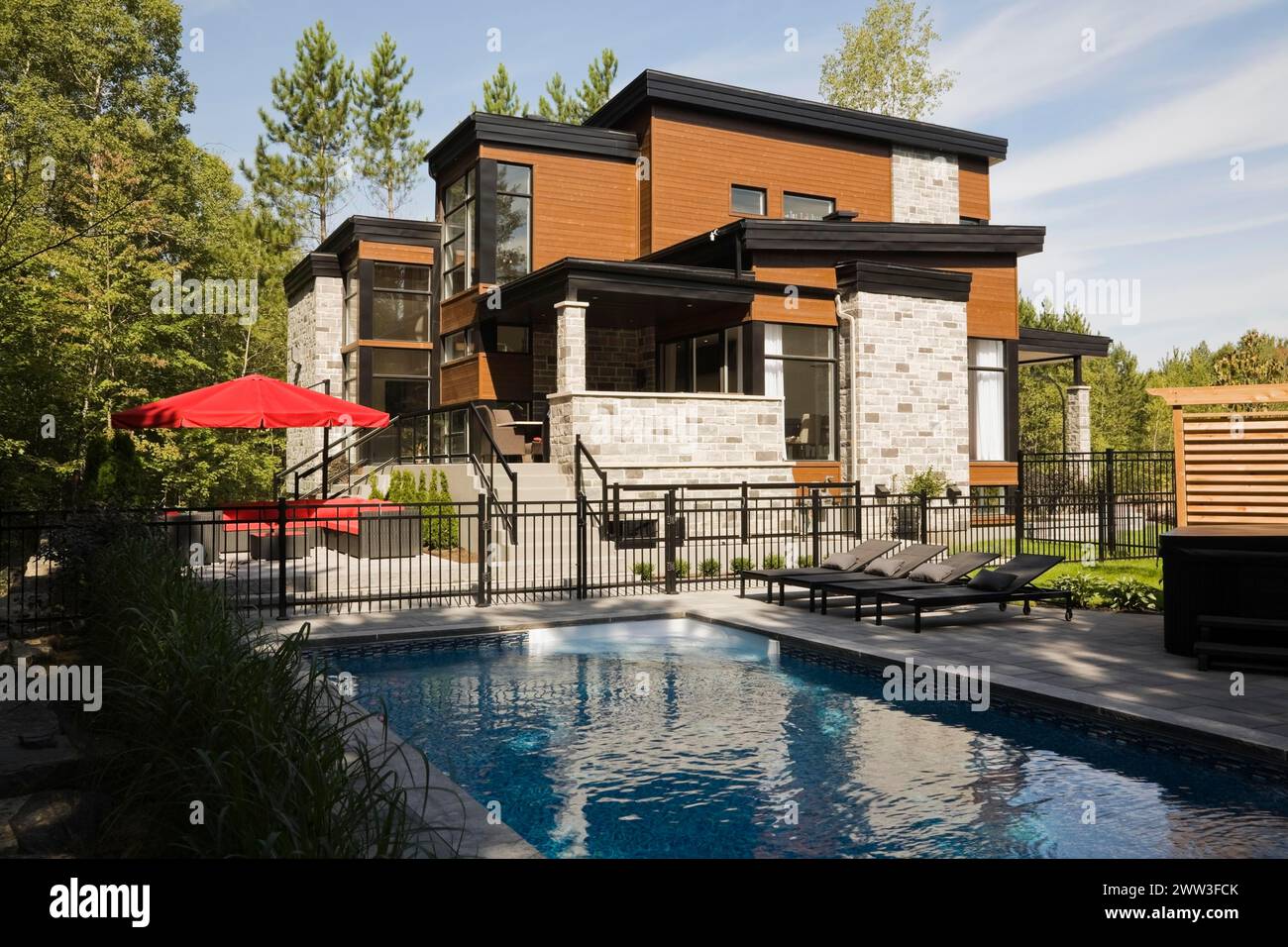 Deux étages gris, beige et beige pierre taillée avec parement en bois et garniture noire maison et piscine creusée en été, Québec, Canada Banque D'Images