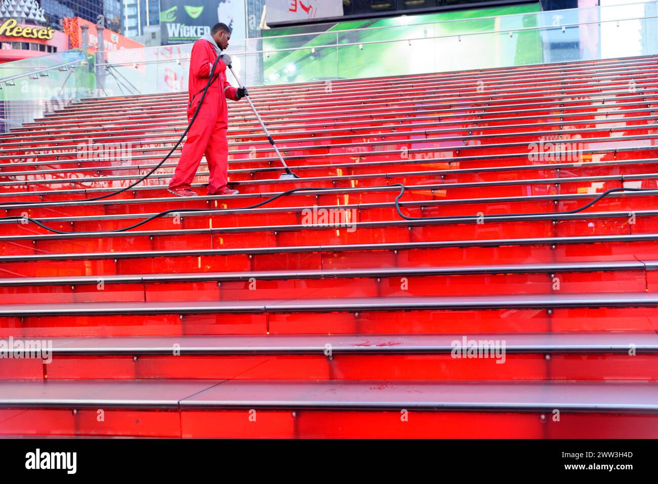 Times Square, personne en salopette rose nettoyant un escalier rouge frappant dans un environnement urbain, Manhattan, New York City, New York, USA, Nord Banque D'Images