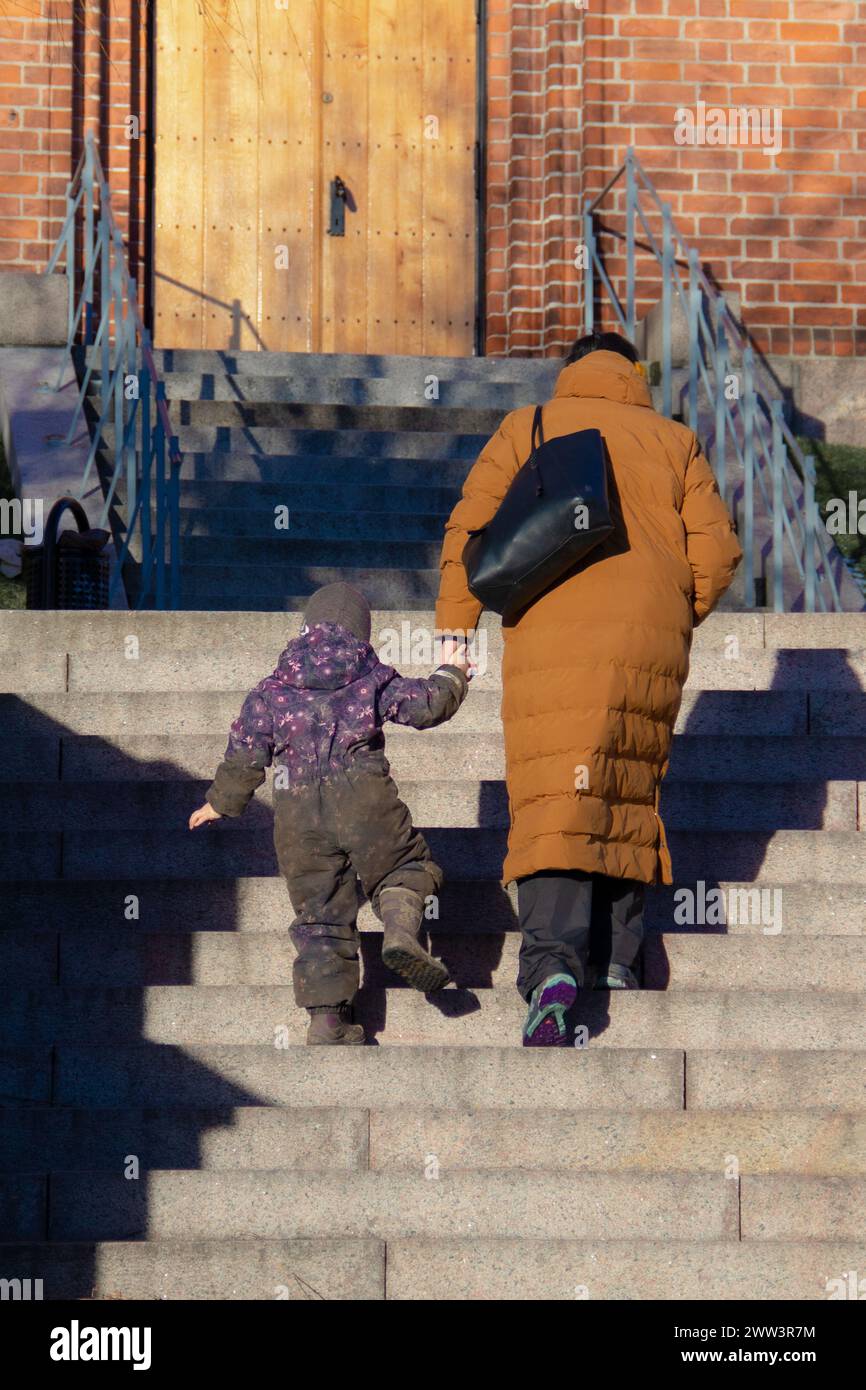 Mère aidant sa fille à monter un escalier dehors Banque D'Images