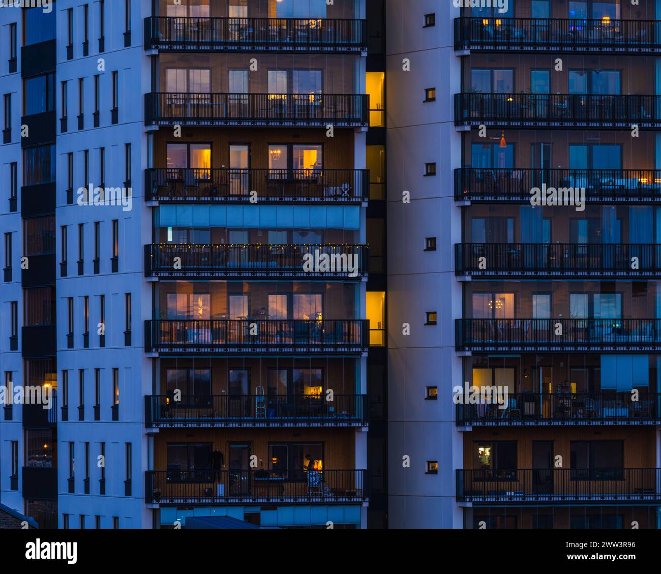 Un grand bâtiment avec de nombreux balcons est éclairé la nuit, mettant en valeur les lumières incandescentes de l'intérieur des chambres et sur les balcons. L'archite Banque D'Images