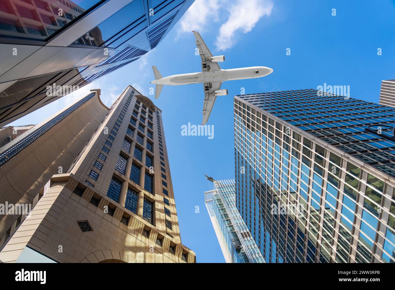 Avion jet volant au-dessus dans le ciel parmi de grands bâtiments dans une métropole de bureaux moderne. Regardez dans le ciel Banque D'Images