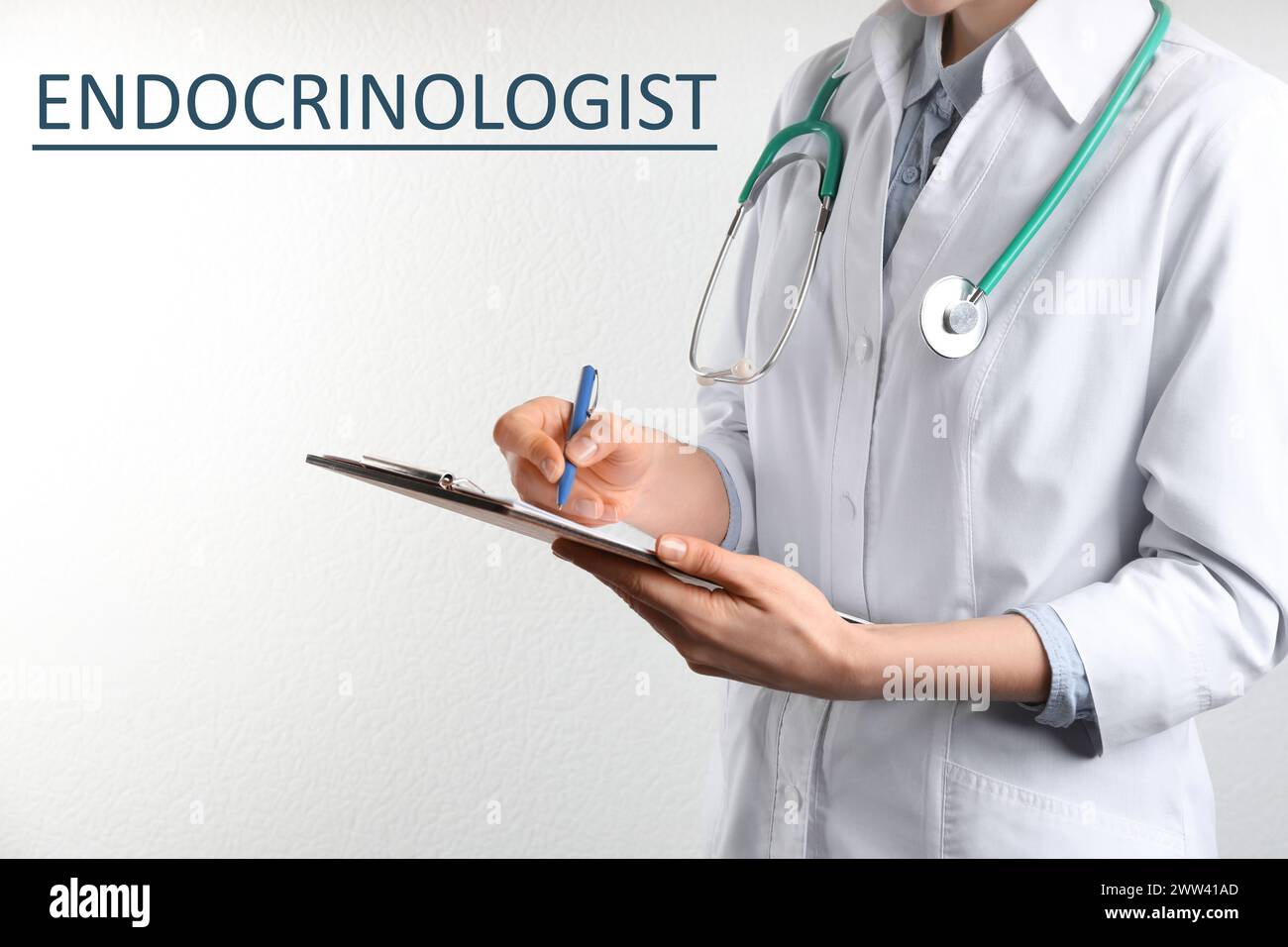 Endocrinologue avec stéthoscope, presse-papiers et stylo près du mur blanc, gros plan Banque D'Images
