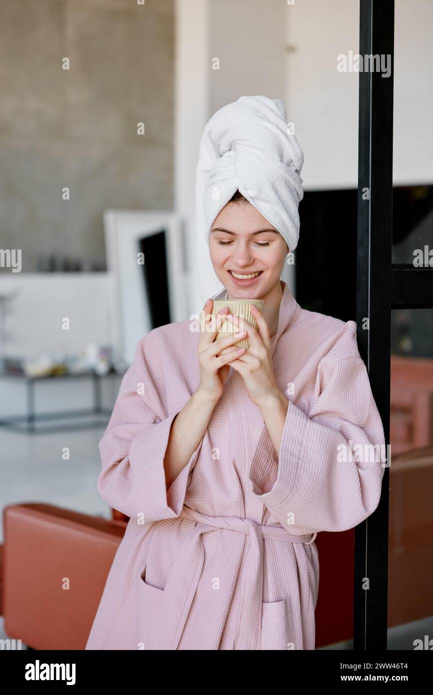 Femme rêveuse pensive buvant du café du matin ou du thé après la douche Banque D'Images