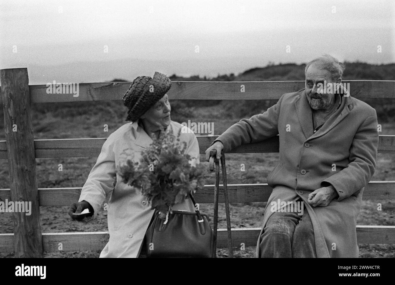 Tansys Golowan ou Baal Fire, St Johns Eve 23 juin Kit Hill Callington, Cornwall 1973. Deux bardes de Cornouailles, M. et Mme Eel, tous deux poètes membres de la Old Cornish Society, récitent des poèmes avant que le feu de joie ne soit allumé. La Dame des fleurs jettera son bouquet d'herbes douces et amères dans les flammes pour encourager le bien et brûler le mal. À travers les Cornouailles, Tansys Golowan est célébré par l'allumage de feux de joie sur les collines. ANNÉES 1970 ROYAUME-UNI HOMER SYKES Banque D'Images