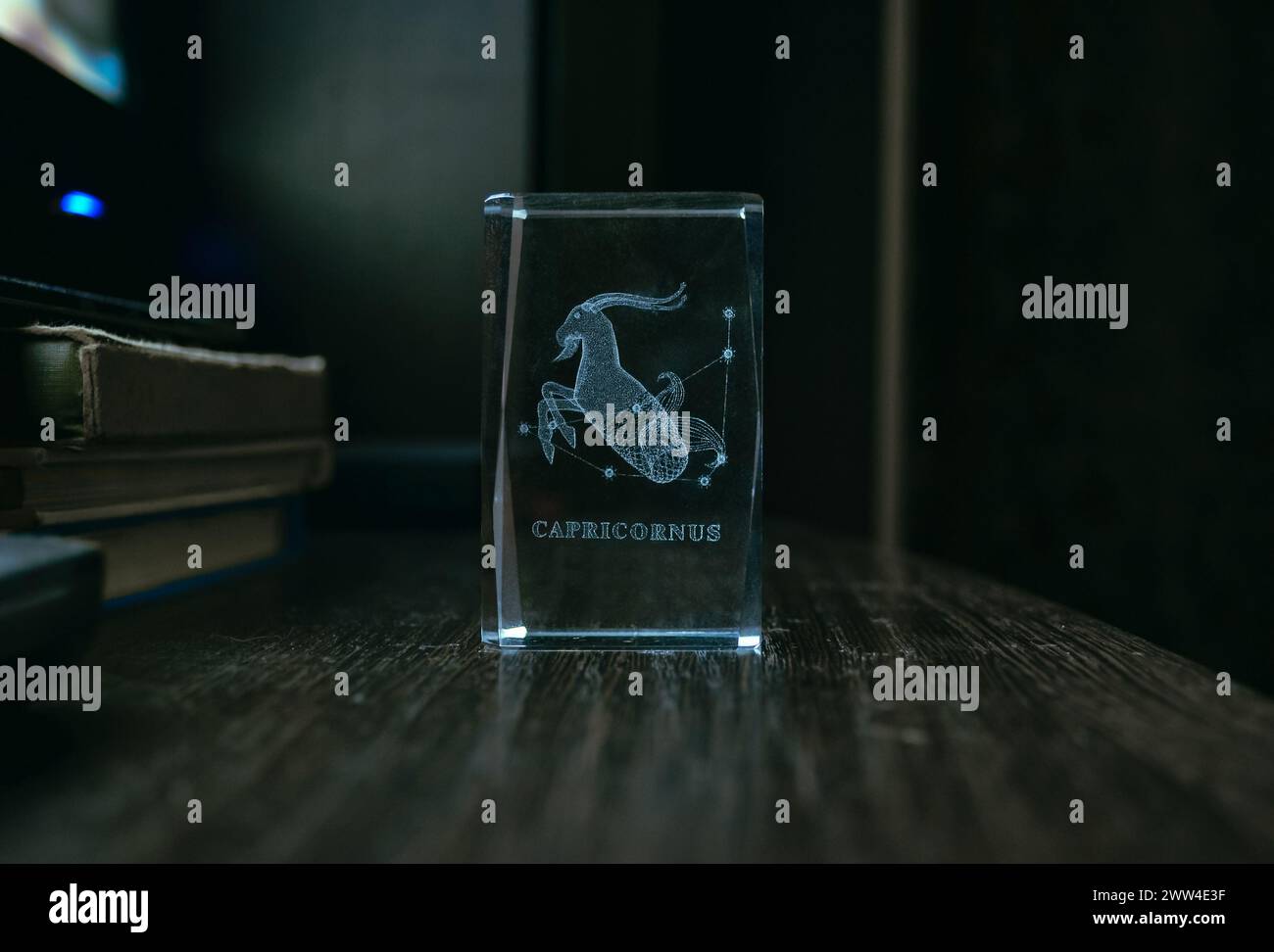Figurine transparente en verre sur fond sombre avec l'image du Capricorne et l'inscription. Horoscope, astrologie et isotères Banque D'Images