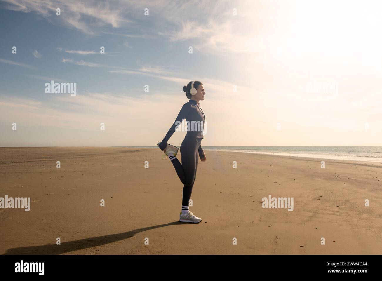 Femme faisant des exercices d'étirement des jambes sur la plage. Routine d'exercices matinaux Banque D'Images