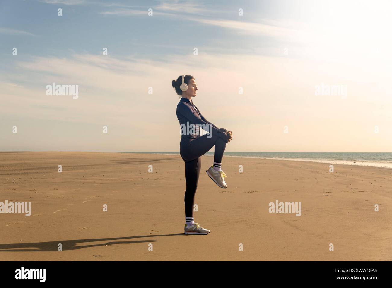 Femme faisant des exercices d'étirement des jambes sur la plage. Routine d'exercices matinaux Banque D'Images