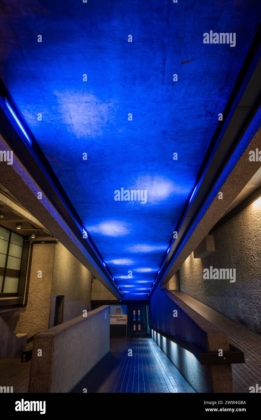 Londres, Royaume-Uni : architecture intérieure du domaine Barbican dans la ville de Londres avec rampe d'accès et lumières bleues. Banque D'Images