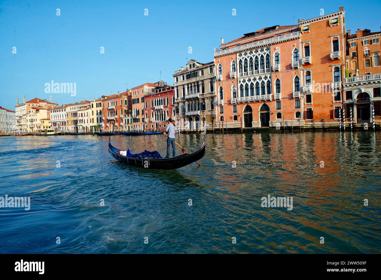 Un homme conduisant une gondole à travers les canaux de Venise, Italie. Tourisme dans la ville de Venise. Patrimoine mondial de l'UNESCO. Banque D'Images