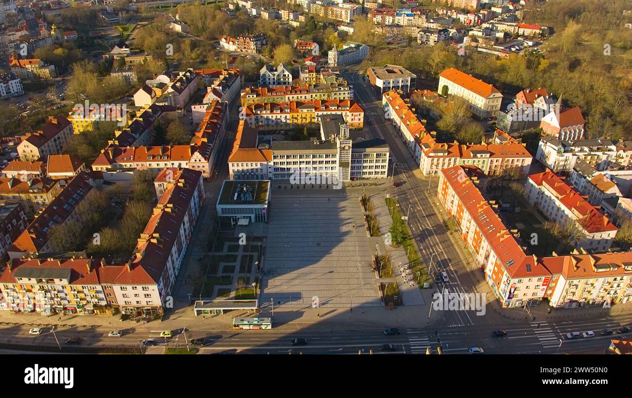 Un drone capture le centre-ville de Koszalin baigné de lumière dorée, avec la cathédrale, Victory Street et l'hôtel de ville. Banque D'Images