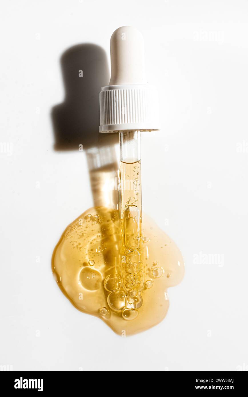 Pipette compte-gouttes et gouttes de sérum doré pour le visage ou de gel de rétinol sur fond blanc. Soin de la peau avec acide ou peptide. Concept de tir cosmétique avec Sha dur Banque D'Images