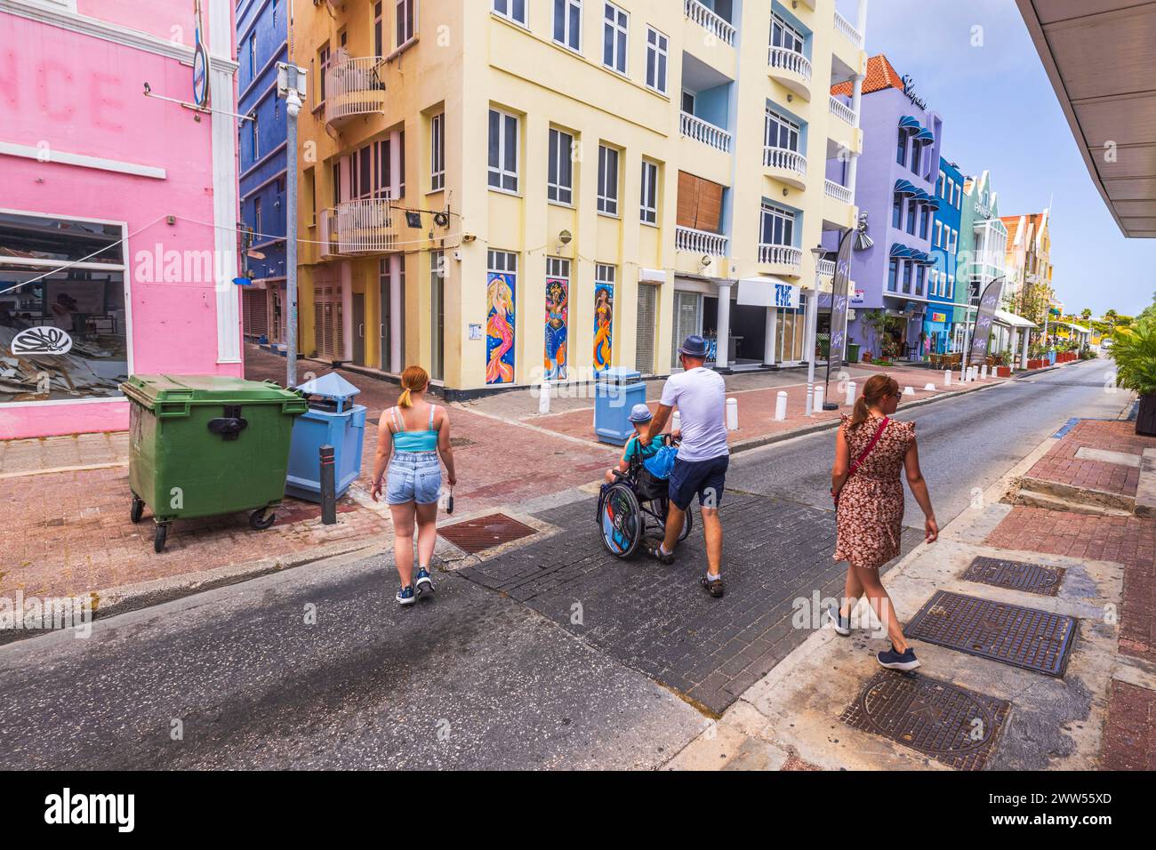 Vue de gens traversant une rue pittoresque à Curaçao, y compris un homme poussant un fauteuil roulant. Willemstad. Curaçao. Banque D'Images