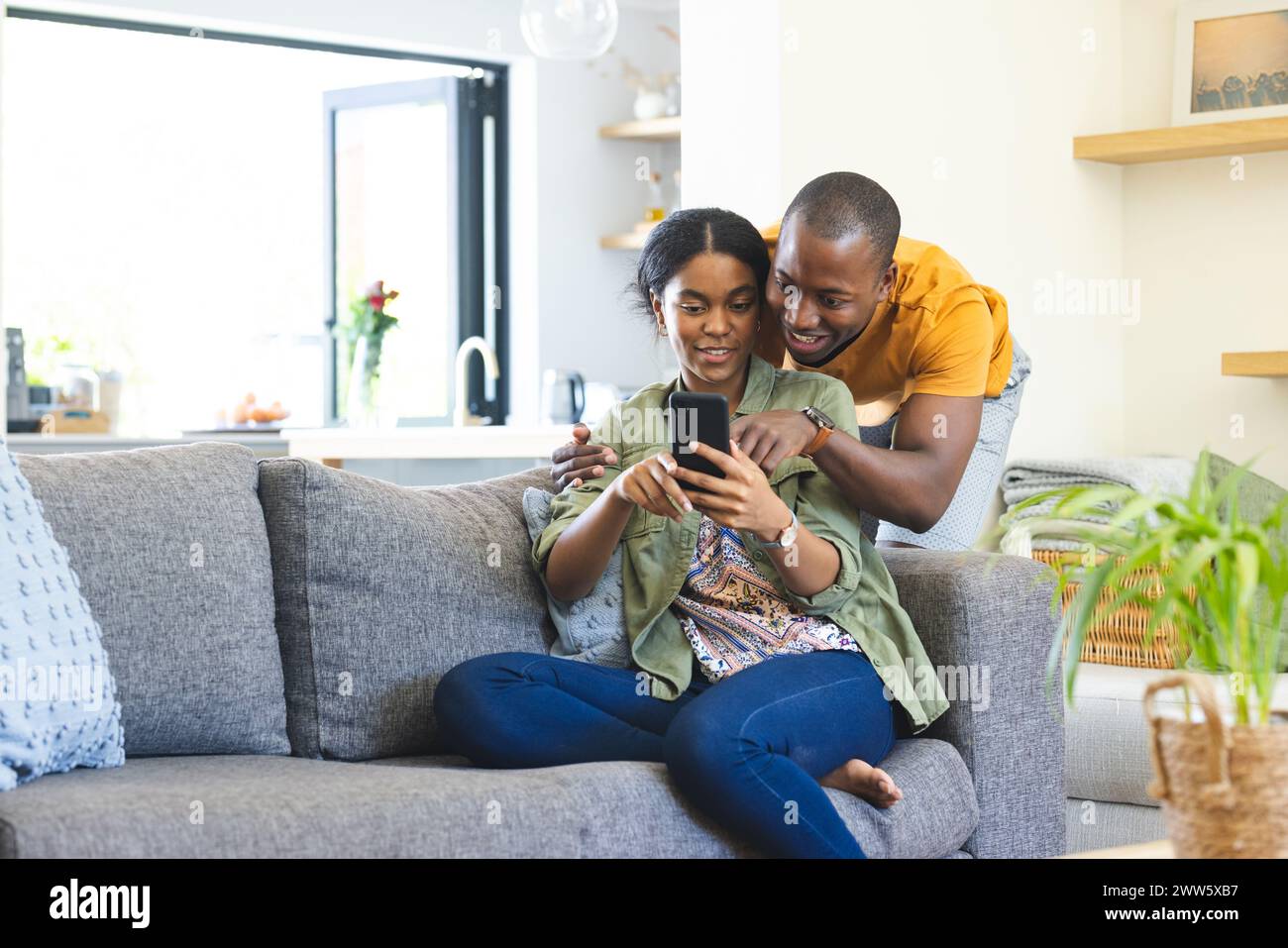 Un couple diversifié utilise un smartphone avec un espace de copie sur le canapé à la maison Banque D'Images