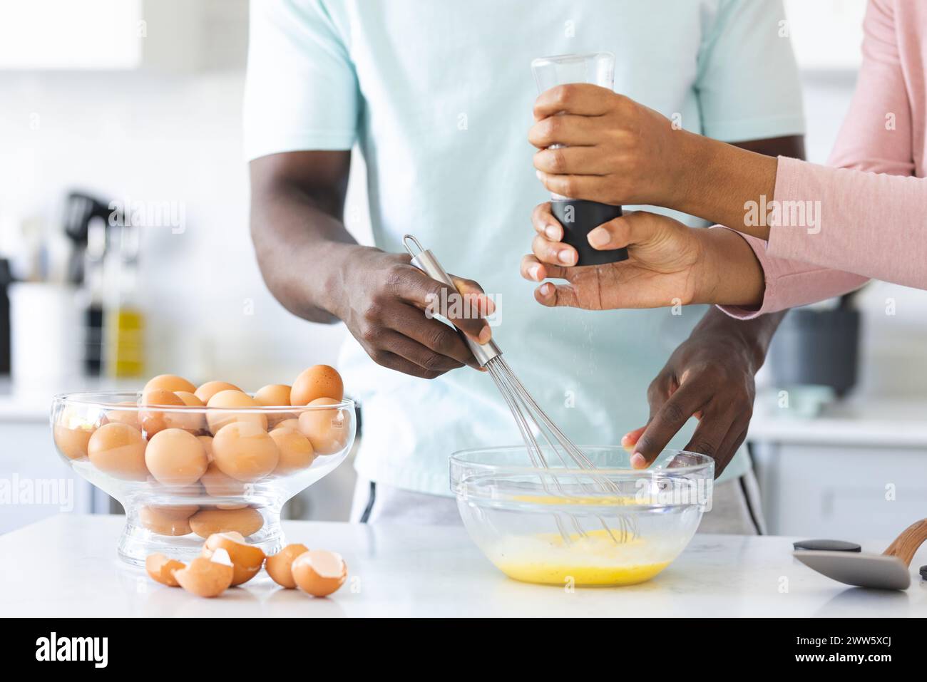 Un couple diversifié prépare un repas ensemble, fait des œufs, dans une cuisine à la maison Banque D'Images