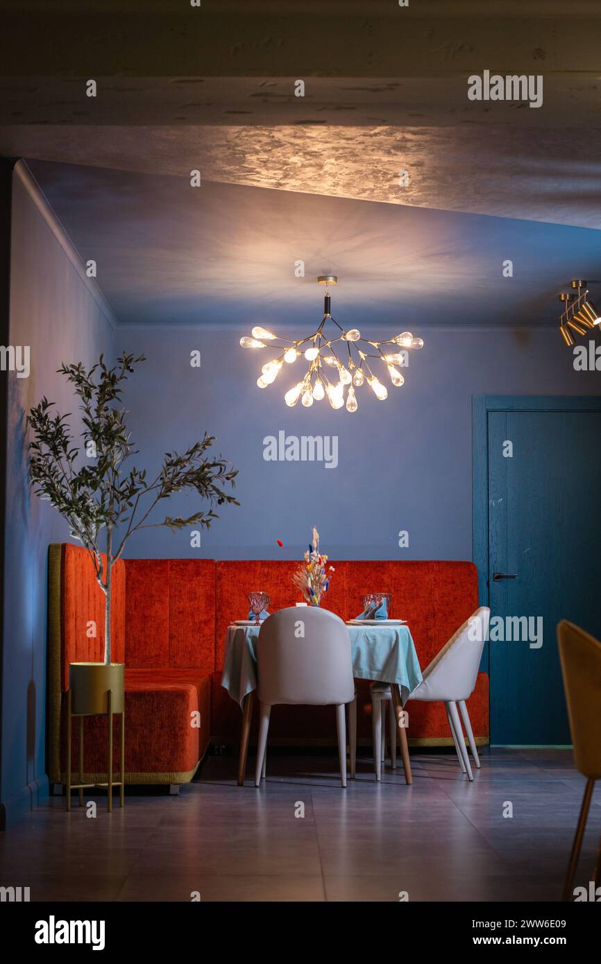 Un bel intérieur de restaurant avec des murs bleus et des meubles en velours rouge. Le restaurant est éclairé par un beau lustre. Banque D'Images