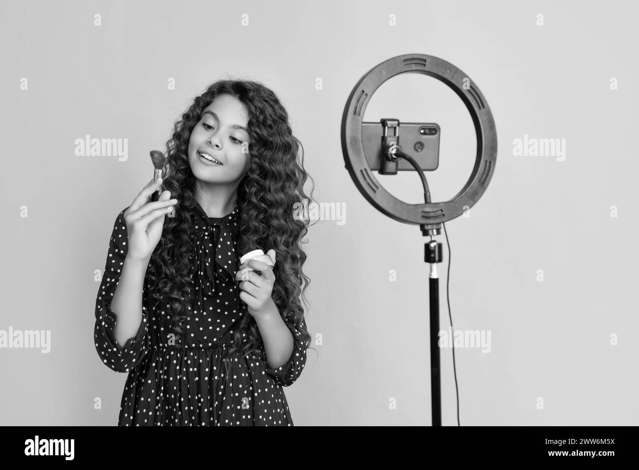 blogueur d'enfant souriant avec les cheveux longs bouclés faire la vidéo pour blog tenir la brosse de poudre Banque D'Images