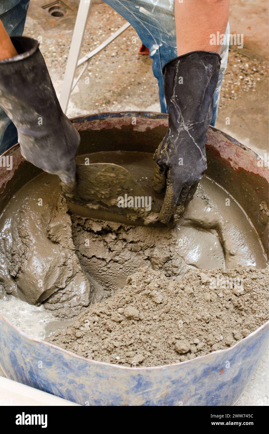 Maçonnerie caucasienne senior mélangeant de l'eau, du ciment et du sable. Banque D'Images