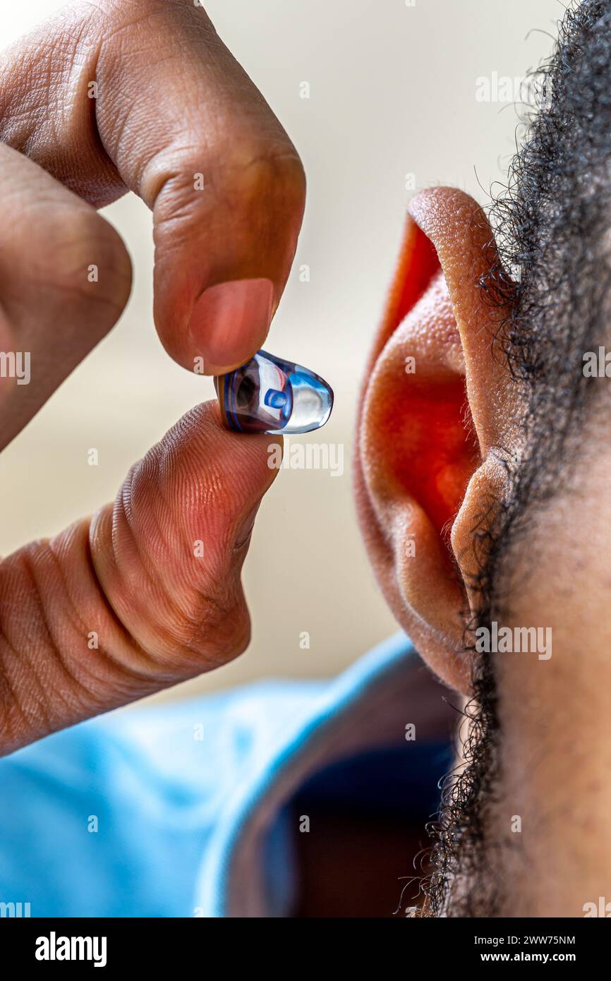 Gros plan sur le positionnement d'une prothèse auditive digitale chez un jeune homme. Banque D'Images