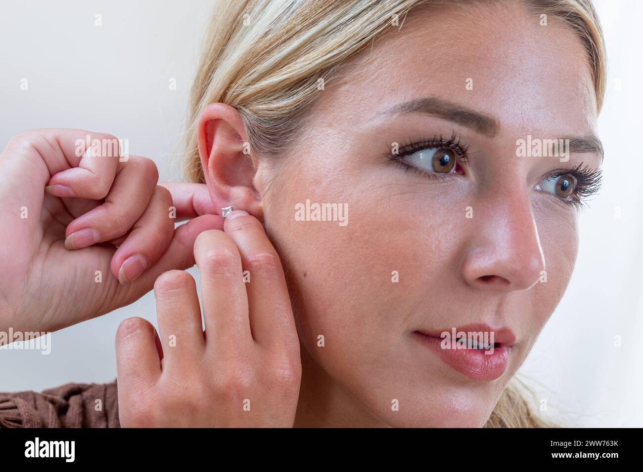 Femme suspendant une boucle d'oreille. Banque D'Images