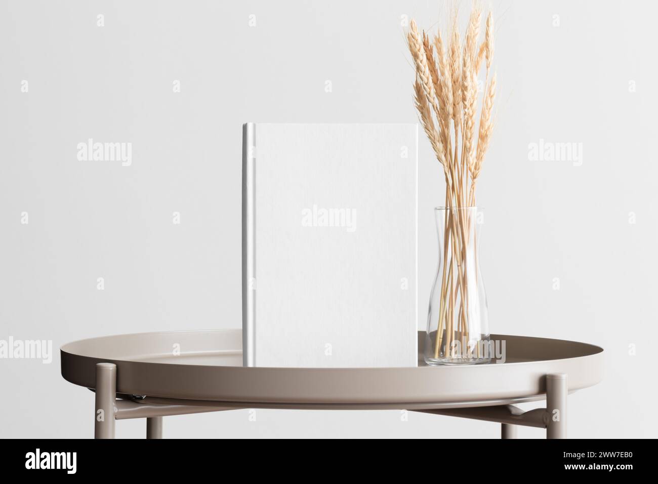 Maquette de livre blanc avec une décoration de fleur de blé sur la table beige. Banque D'Images