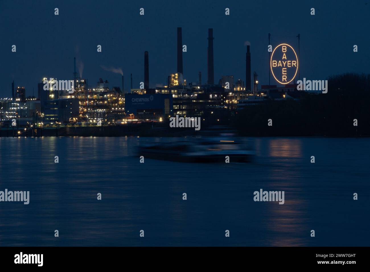 Blick auf den Chempark Leverkusen, Bayer-Werk, Lanxess, Covestro, Bayer-Kreuz, im Vordergrund der Rhein mit einem Frachtschiff, gesehen BEI Einbruch der Daemmerung vom Westufer des Rheins in Koeln-Mengenich, AM 21.03.2024, *** vue du Chempark Leverkusen, Bayer Plant, Lanxess, Covestro, Bayer Kreuz, au premier plan, le Rhin avec un cargo, vu au crépuscule depuis la rive ouest du Rhin à Koeln Mengenich, le 21 03 2024, Banque D'Images