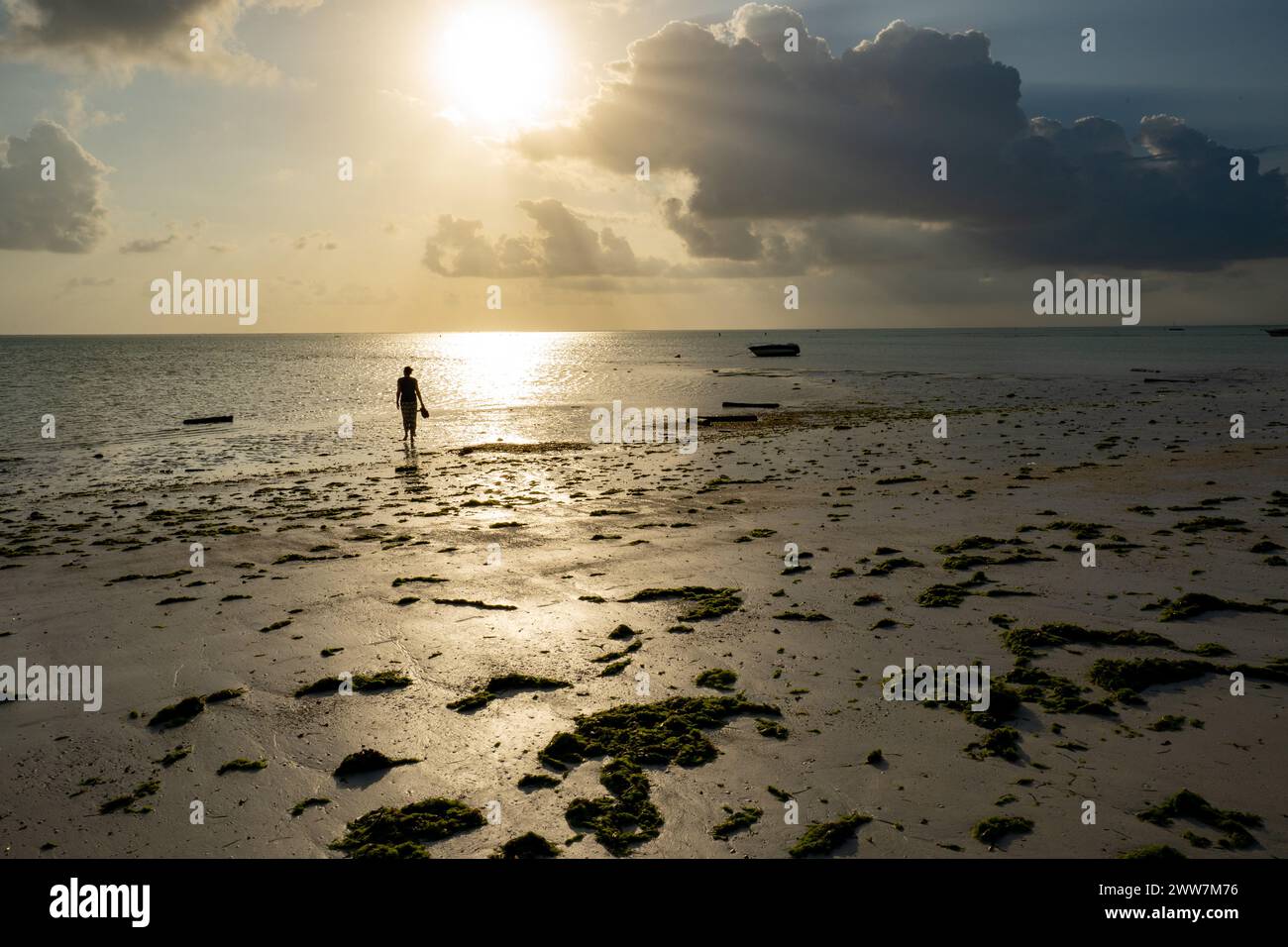 Les touristes flânent sur la plage au coucher du soleil. Photographié sur la côte est de Zanzibar Banque D'Images