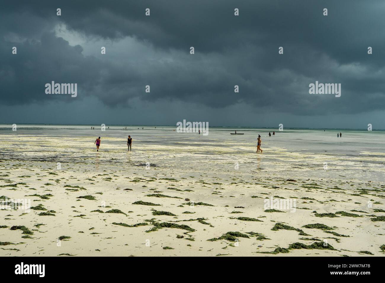 Les touristes flânent sur la plage au coucher du soleil. Photographié sur la côte est de Zanzibar Banque D'Images