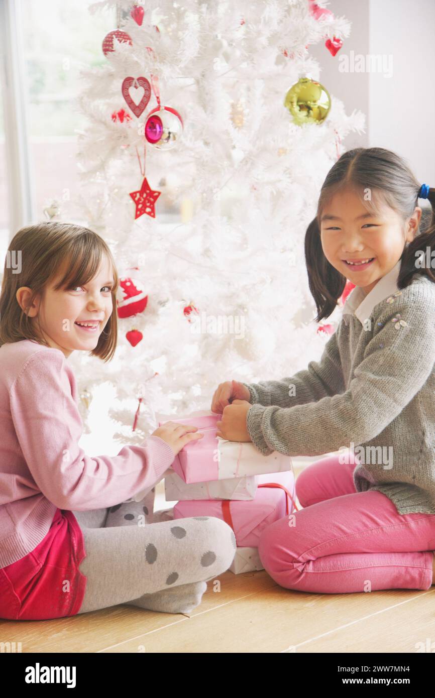 Deux jeunes filles de l'ouverture des cadeaux sous l'arbre de Noël, Smiling Banque D'Images