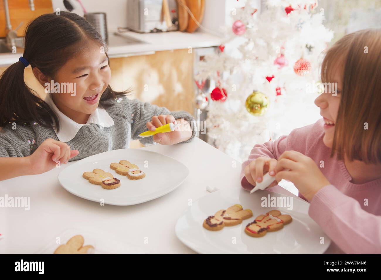 Deux jeunes filles décorant le pain d'épice Biscuits homme Banque D'Images