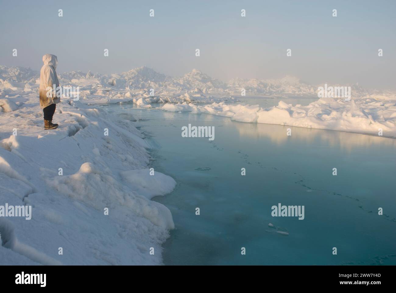 Un chasseur de subsistance Inupiaq se tient sur la banquise rugueuse, après avoir observé des conditions instables de glace de mer non loin du rivage, la mer des Tchouktches Alaska Banque D'Images