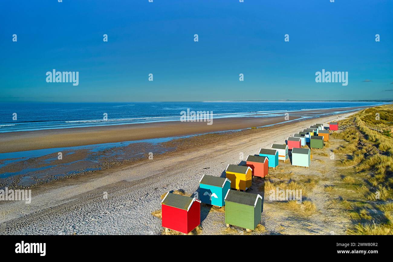 Findhorn Moray Coast Scotland une rangée de cabanes de plage colorées surplombant la plage de sable et de galets et la mer bleue Banque D'Images