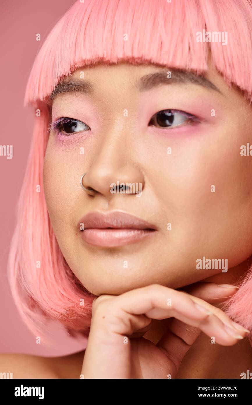 gros plan de fille asiatique séduisante avec des cheveux roses soutenant au menton avec la main et regardant sur le côté Banque D'Images