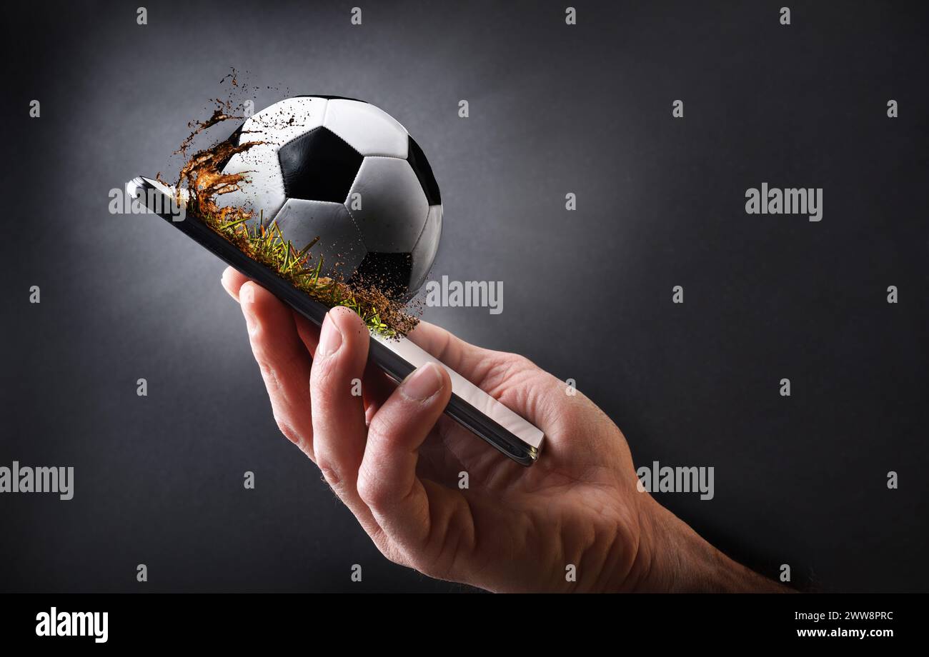 Concept de regarder le football en ligne avec la main tenant un téléphone portable avec balle et fond isolé gris foncé. Banque D'Images