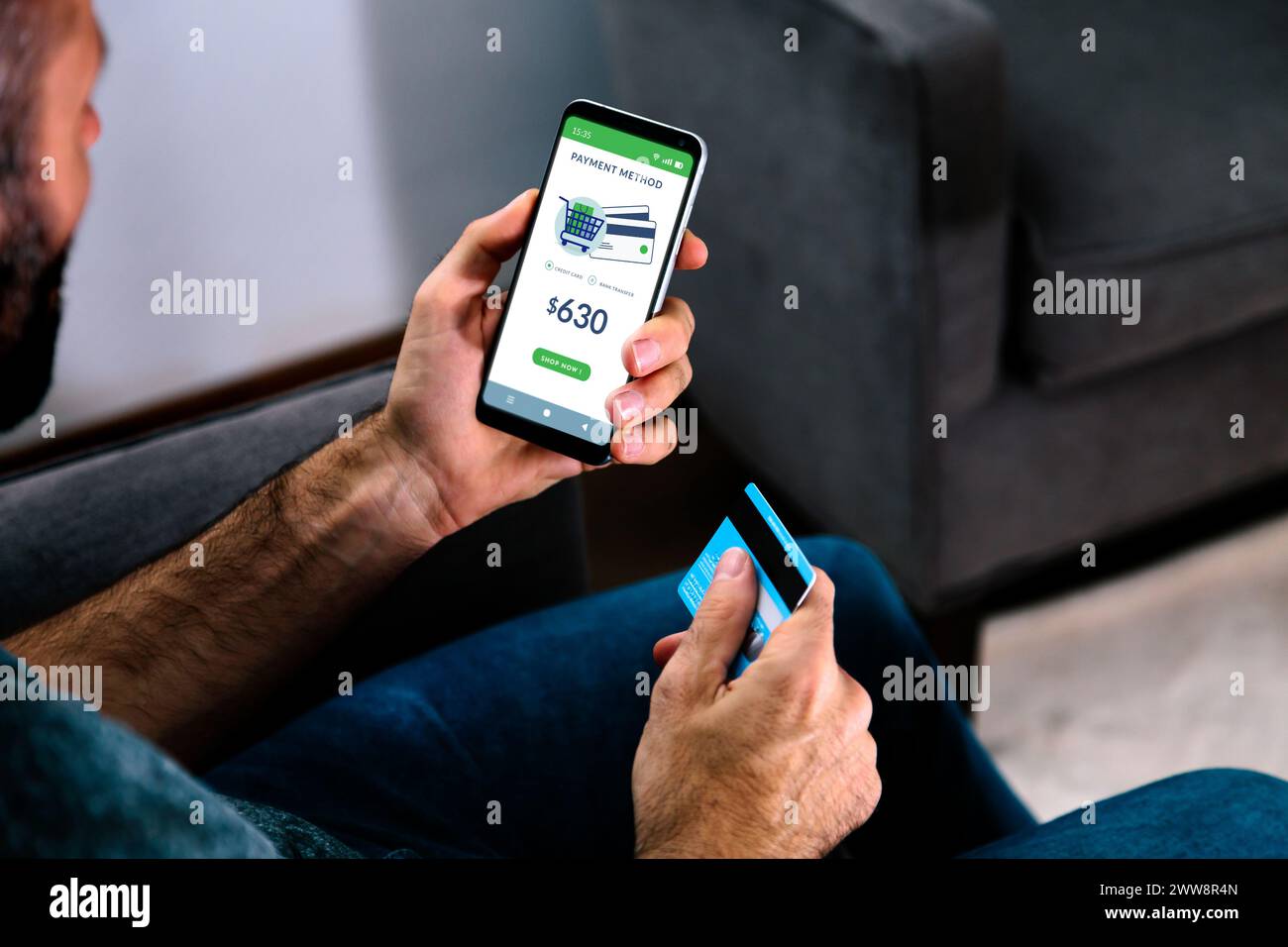 Homme tenant une carte de crédit et un téléphone portable sur le point de payer un achat en ligne. Banque D'Images