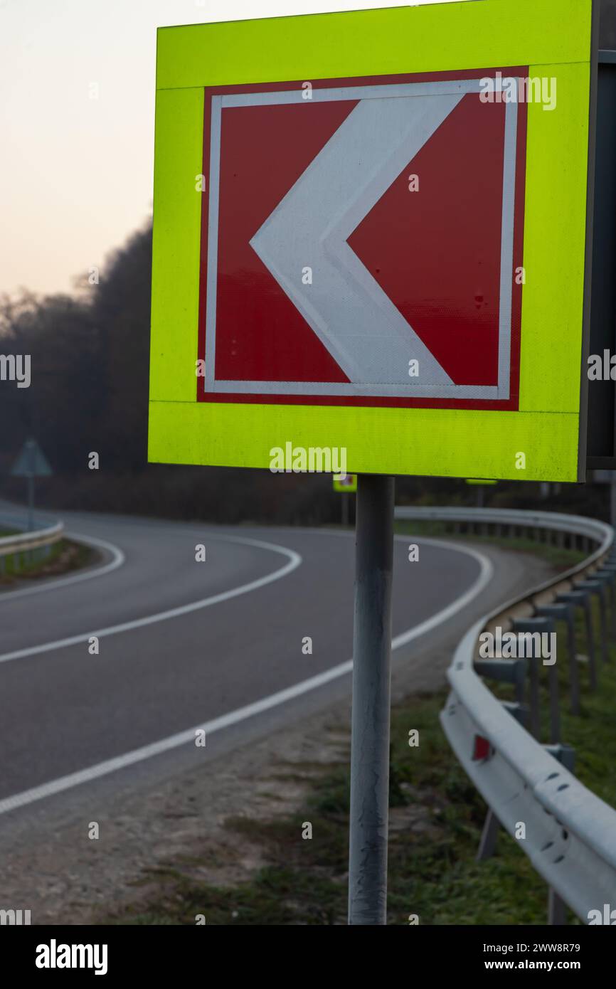 Route asphaltée avec des panneaux de signalisation lumineux in situ du virage à gauche serré. Banque D'Images