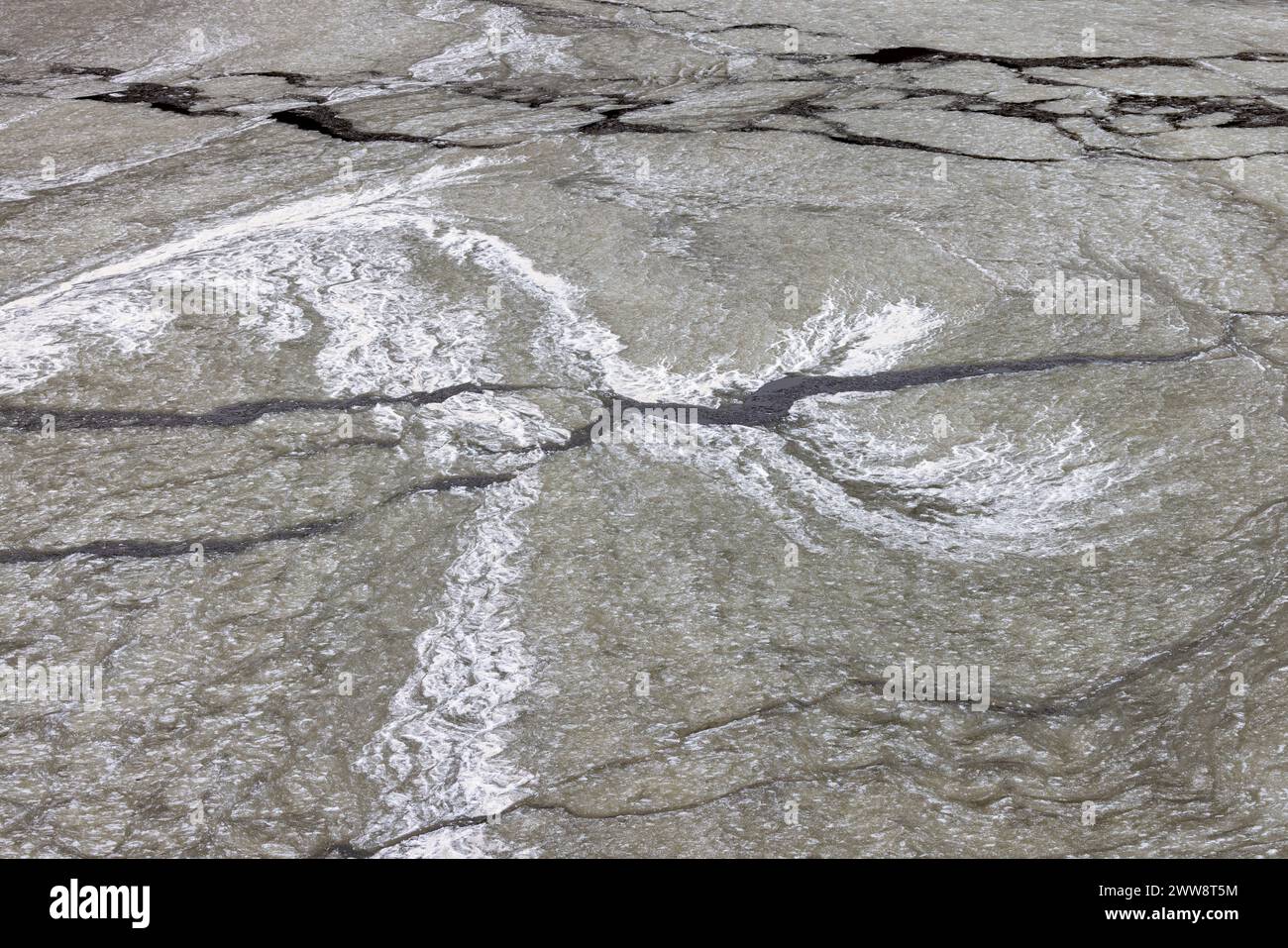 Fissure de glace gelée avec de l'eau noire coulante Banque D'Images