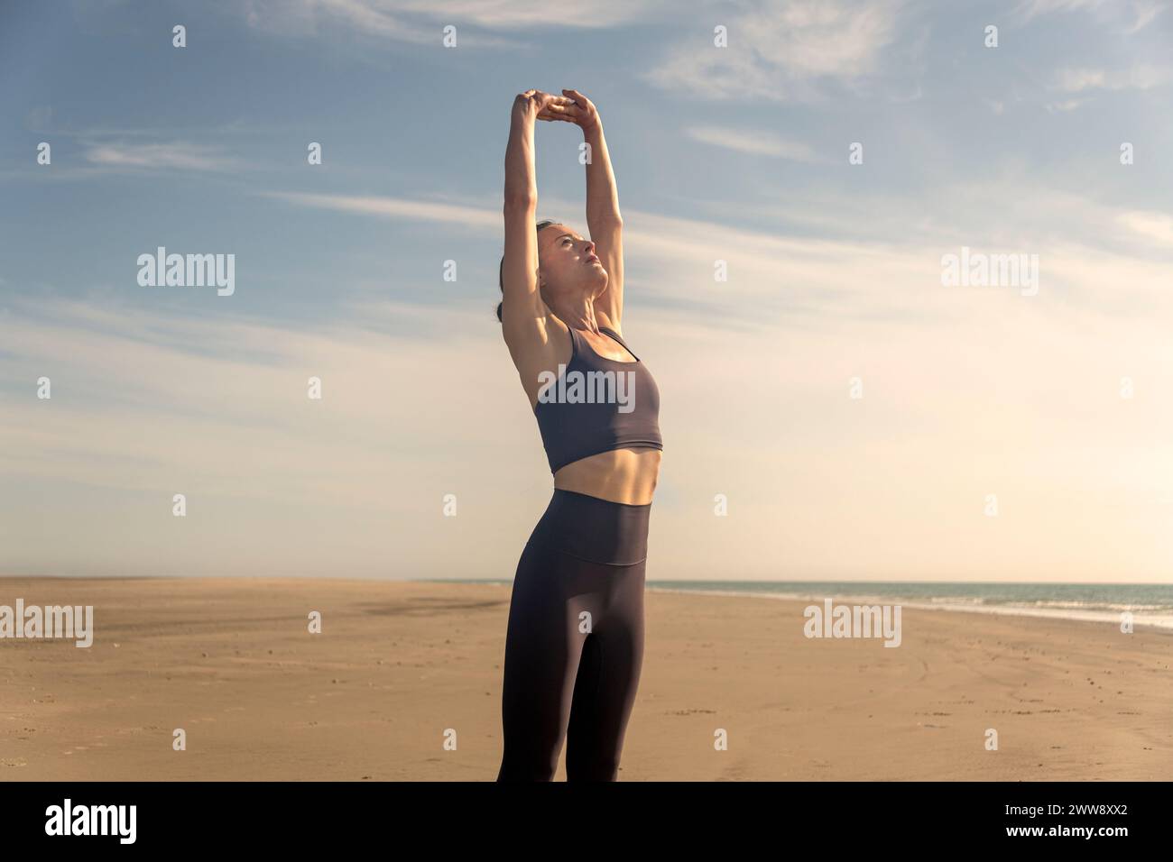 Femme sportive faisant des exercices d'étirement sur la plage, s'entraînant à l'extérieur. Exercices d'échauffement à la plage. Banque D'Images