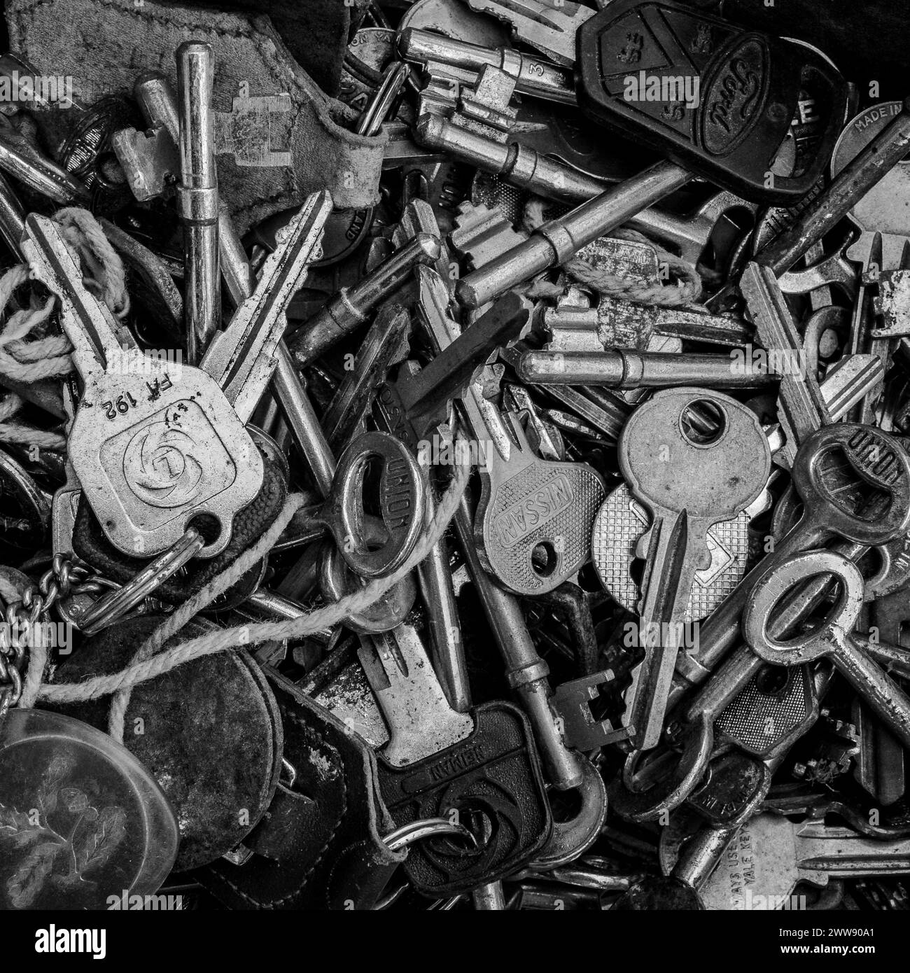 Gros plan d'un plateau de vieilles clés de voiture, clés de maison et clés antiques. Métal brillant, métal rouillé. Concept - serrures, sécurité, sûreté, portes. Noir et blanc Banque D'Images