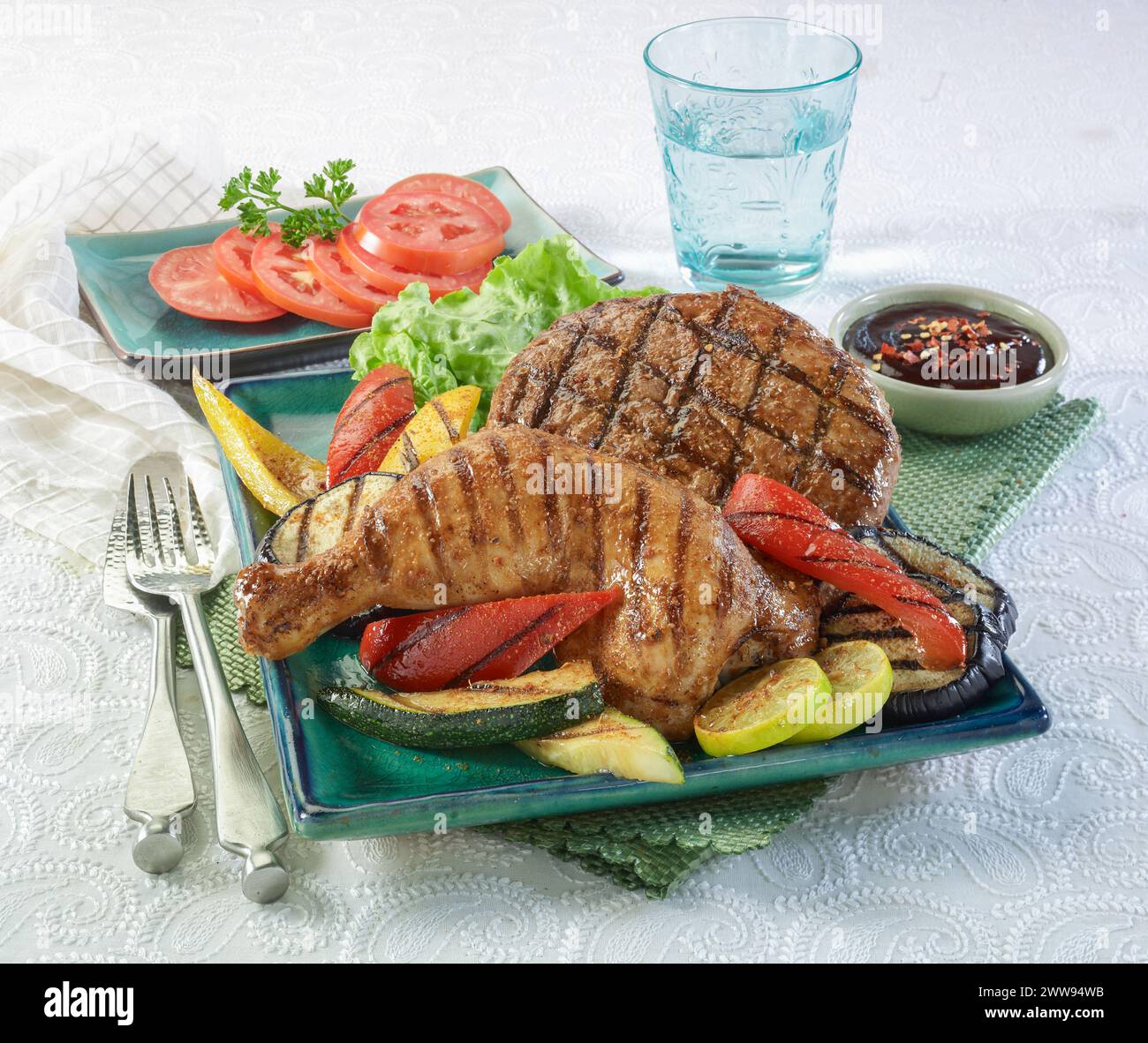 Patty hamburger de poulet et de bœuf grillé avec légumes grillés, sauce piment et tomates Banque D'Images