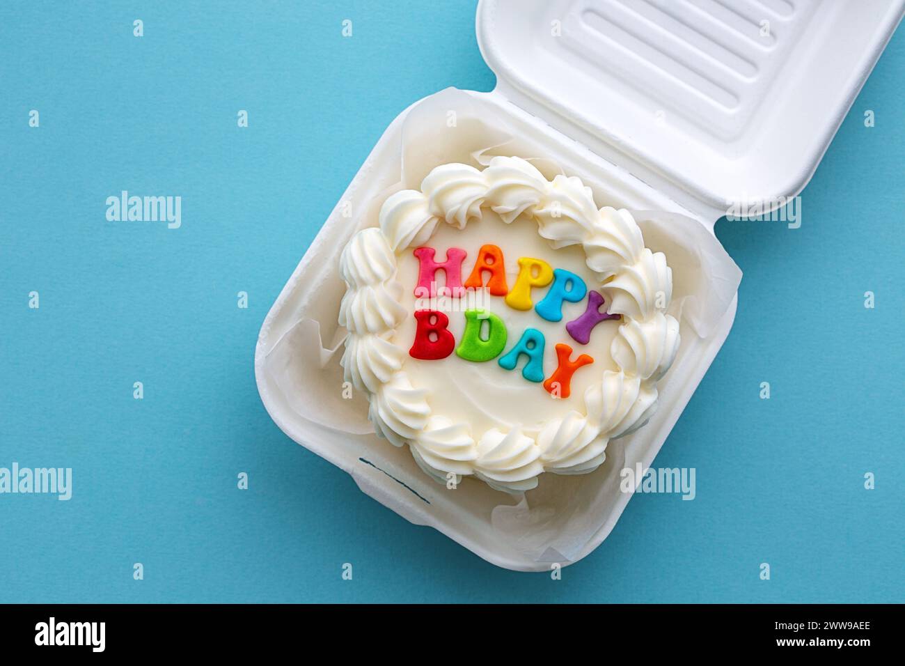 Mini gâteau d'anniversaire avec message coloré joyeux anniversaire dans une boîte à lunch en carton Banque D'Images