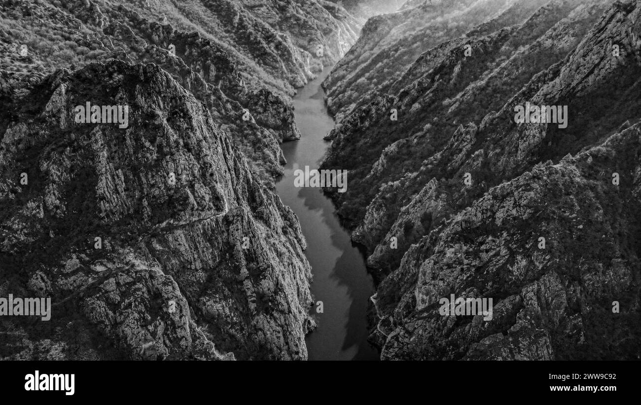 Une image en noir et blanc d'une rivière avec des montagnes lointaines à Skopje Banque D'Images