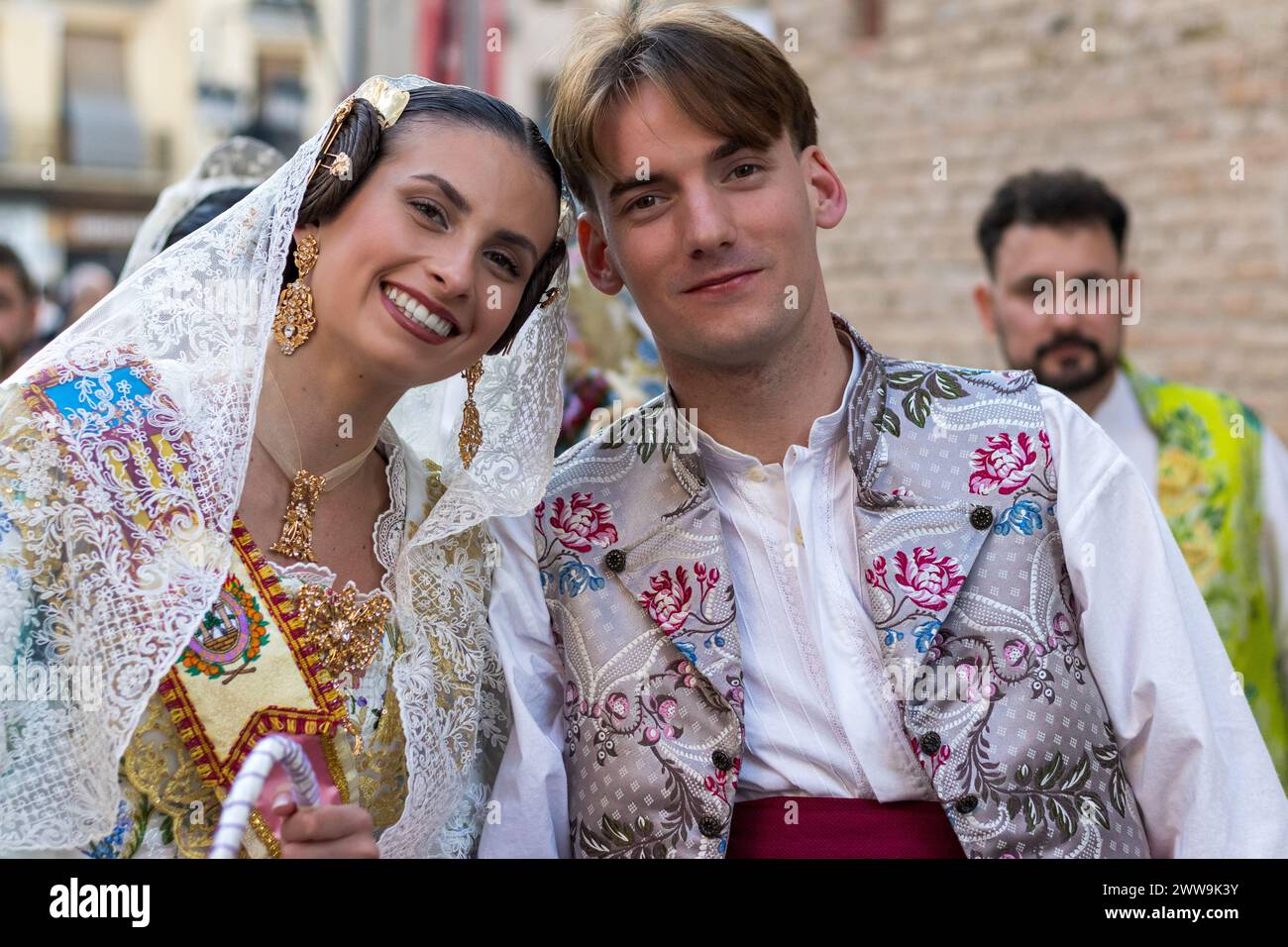 Une robe crème de Fallera et l’ensemble vibrant d’un homme racontent une histoire de tradition. Leur tenue, une tapisserie de broderie florale et de teintes dorées, célèbre Banque D'Images