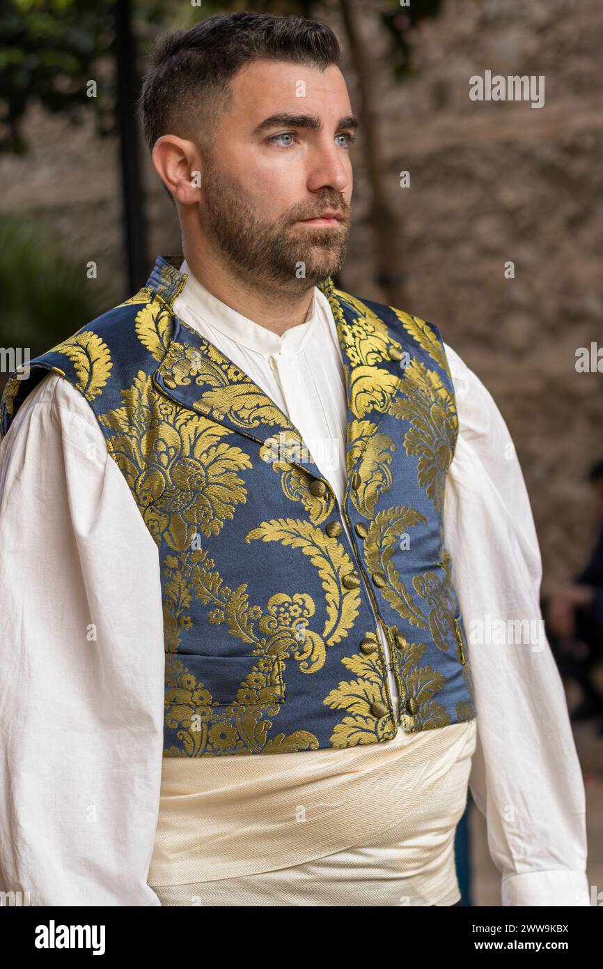 Un portrait de la tradition : vêtements de Fallas en plein écran. Dans les rues festives de Gandia, le costume d’un homme raconte l’histoire et la célébration. Banque D'Images