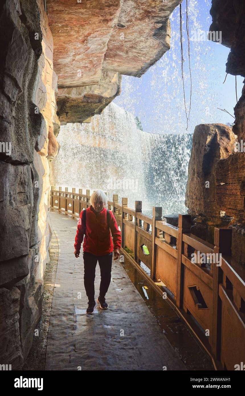 Un touriste se promène sous le tunnel rideau de Kunming Waterfall Banque D'Images