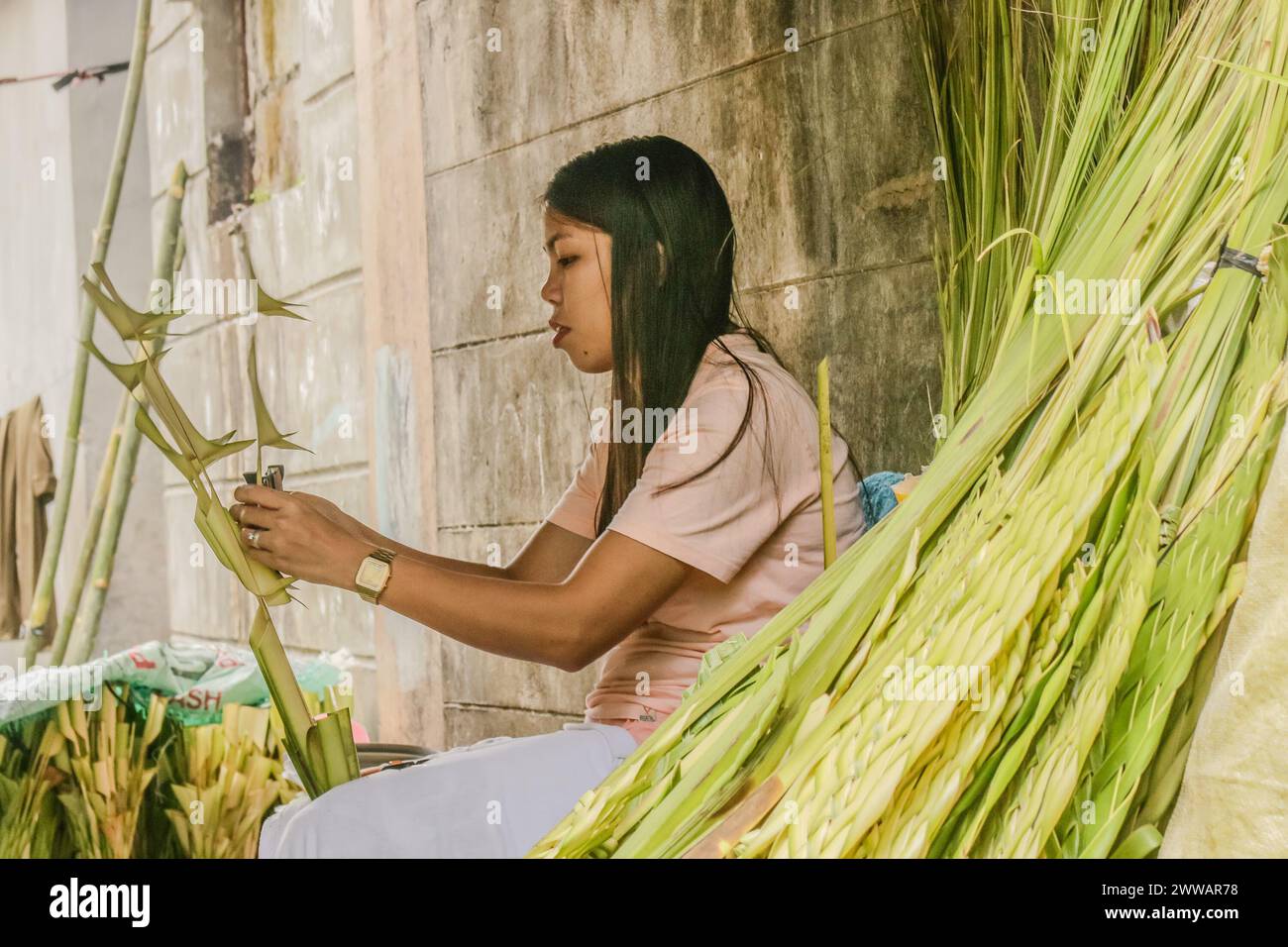 Antipolo City, Rizal, Philippines. 23 mars 2024. Les gens préparent des branches de palmier à côté de la rue en commémoration du dimanche des Rameaux à Antipolo City, Philippines, le 23 mars 2024. Les frondes de palmier ont été historiquement liées à la victoire et au triomphe dans de nombreuses cultures. Les fidèles catholiques symbolisent le dimanche des Rameaux comme le début de la semaine Sainte. (Crédit image : © Ryan Eduard Benaid/ZUMA Press Wire) USAGE ÉDITORIAL SEULEMENT! Non destiné à UN USAGE commercial ! Banque D'Images