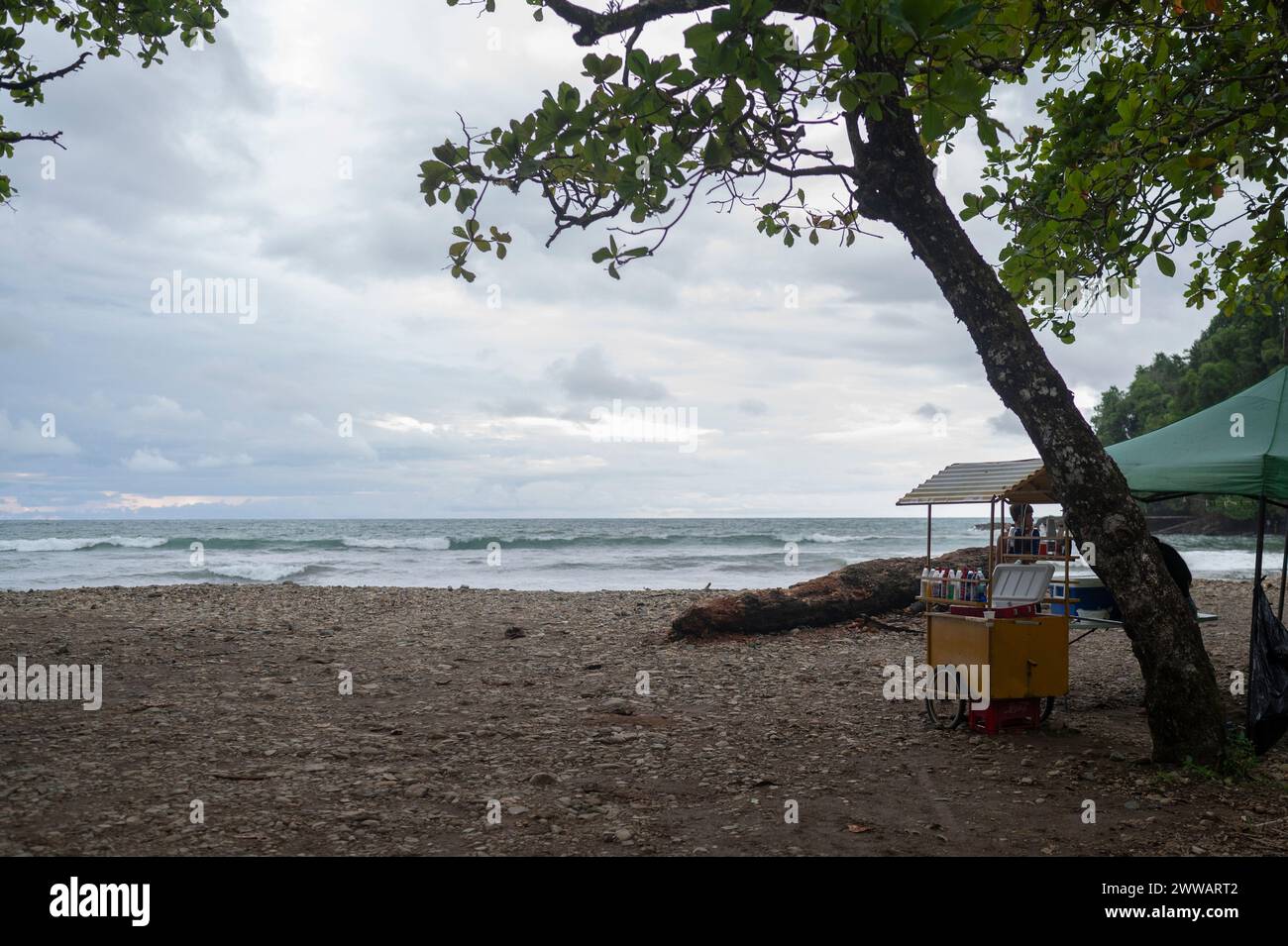 Un petit chariot vendant des collations et des boissons près d'un océan tropical. Banque D'Images