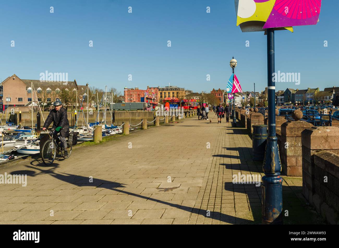 Bangor, County Down, Irlande du Nord 20 mars 2024 - les gens marchent et font du vélo le long de la promenade près de la marina de Bangor Co. Bas Banque D'Images