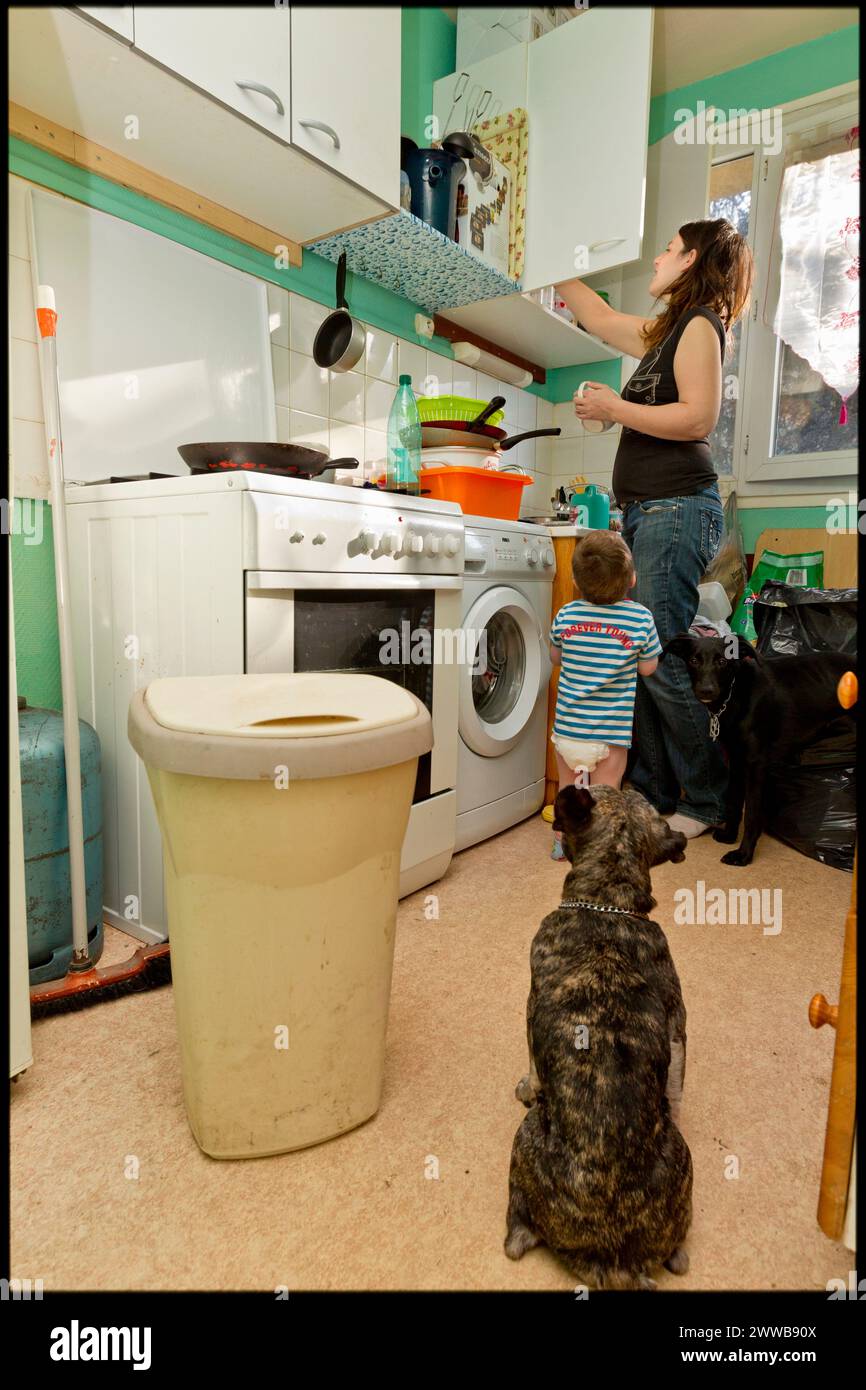 ASE - aide sociale à l'enfance. Pendant que la mère ranger les placards de la cuisine, Maxence, 2 ans, essaie d'attirer son attention. UTILISATIONS ÉDITORIALES UNIQUEMENT. Banque D'Images